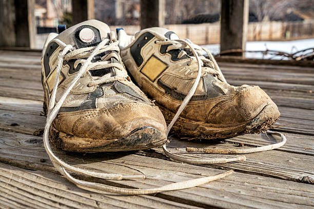 a pair of old muddy running shoes against wooden deck